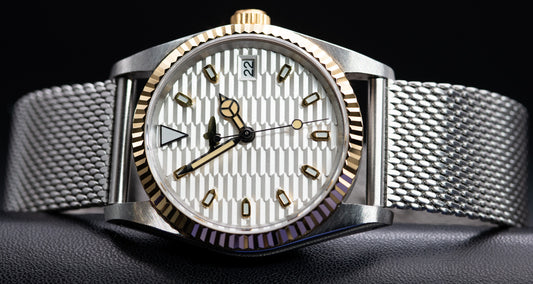 Two Tone fluted bezel watch in vintage style case. two tone fluted dial. drilled lugs. stainless steel mesh bracelet